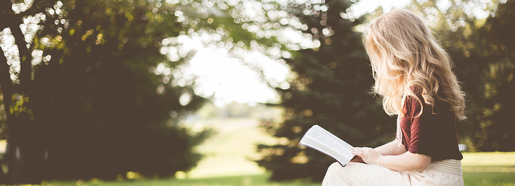 Denver Bible studies - woman reading Bible outdoors in field